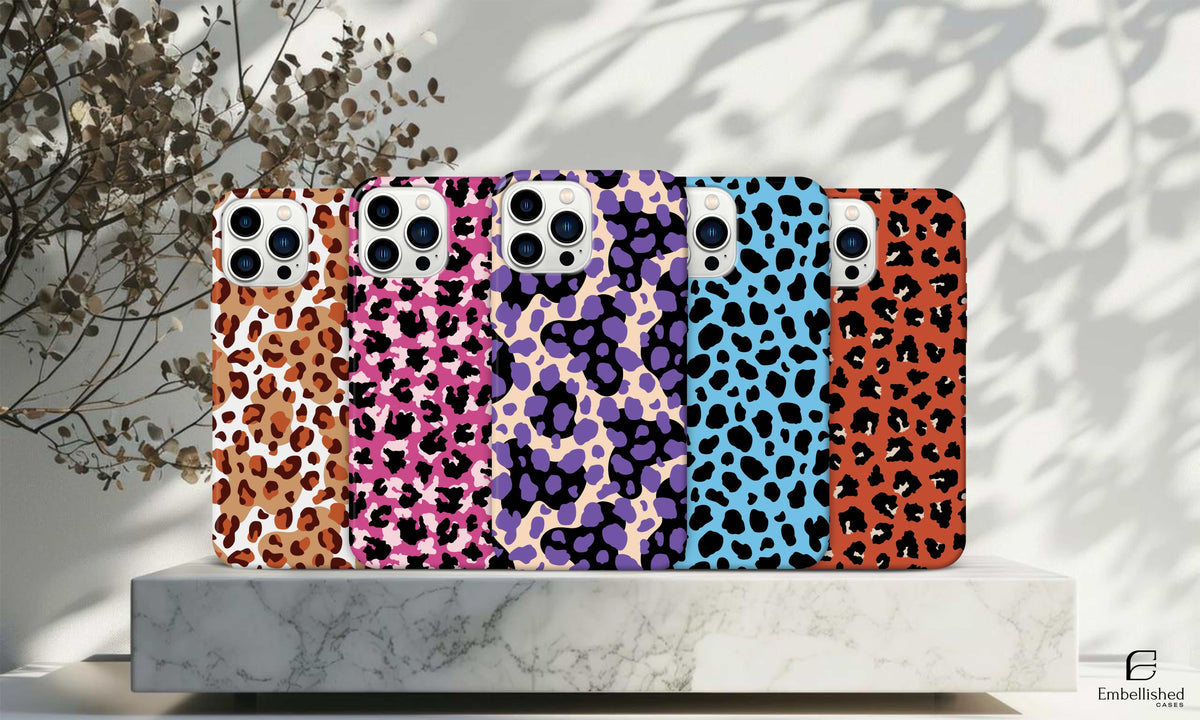 Leaves clear phone case with colorful leopard print design on various smartphone models displayed on marble surface