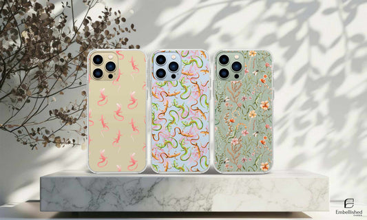 Clear phone cases with lizard and floral designs on a marble surface, wild flower cases.