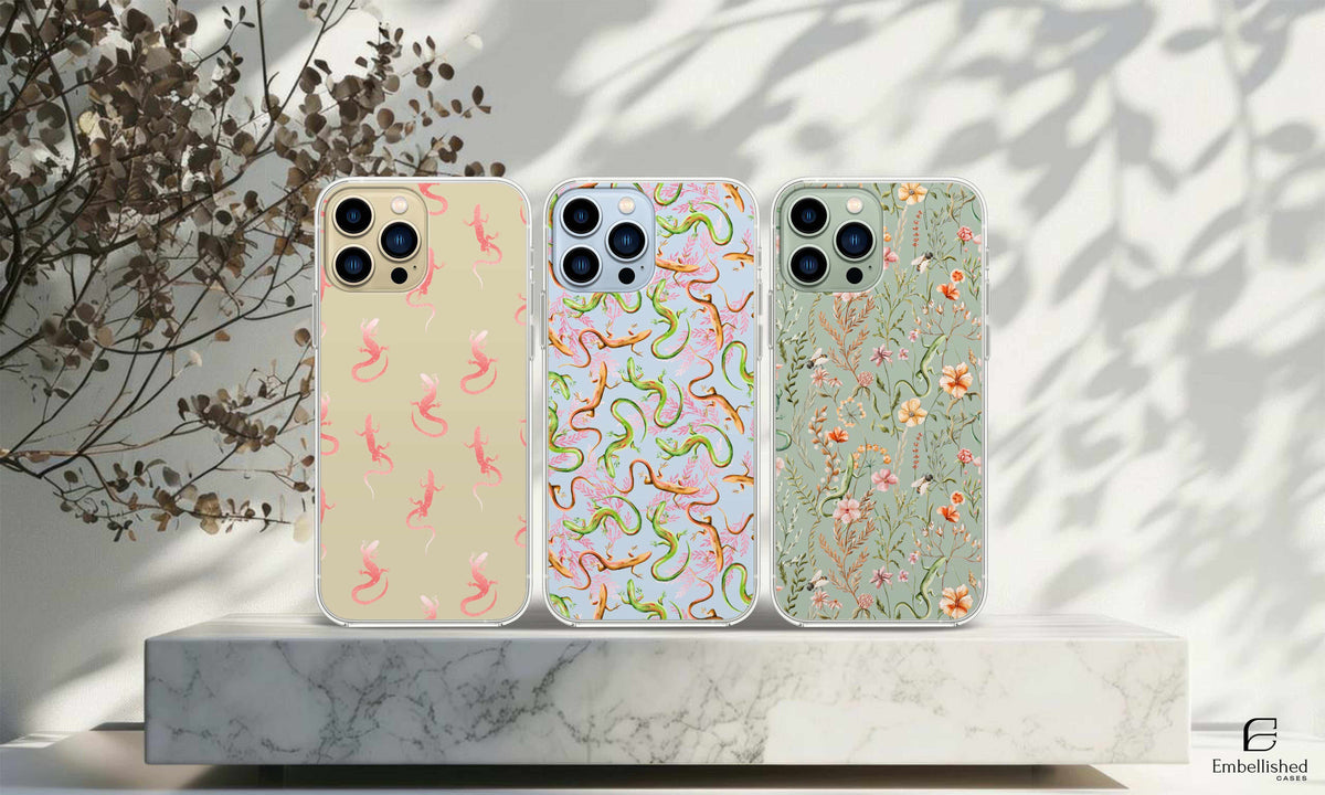 Clear phone cases with lizard and floral designs on a marble surface, wild flower cases.